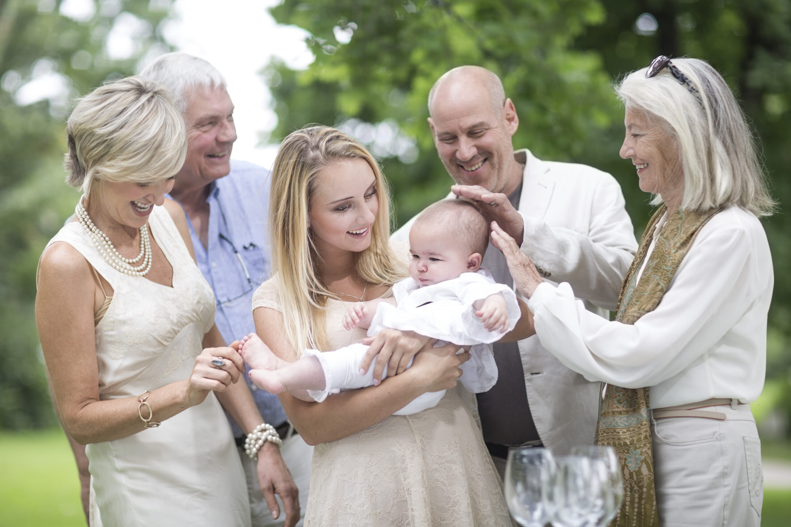 Family gathering around baby outdoors